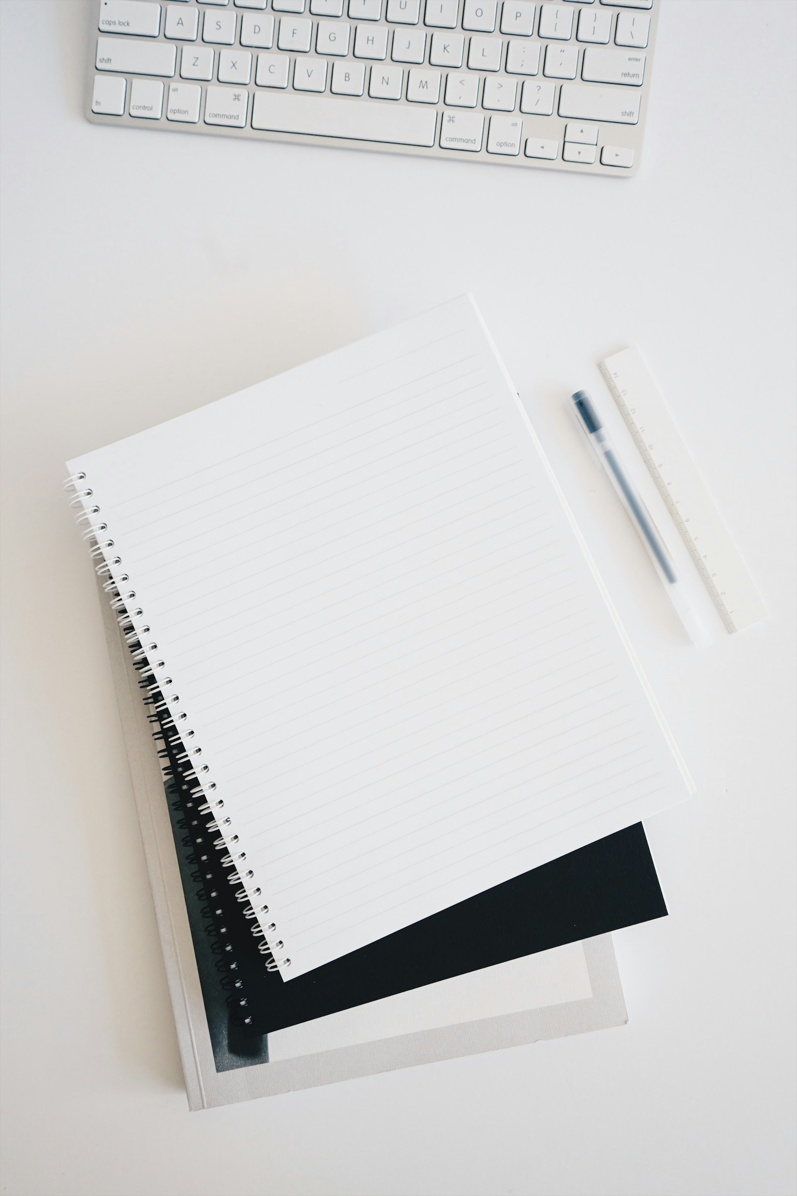 Notebook, pen, and ruler laid out beside a keyboard — early discovery and research notes